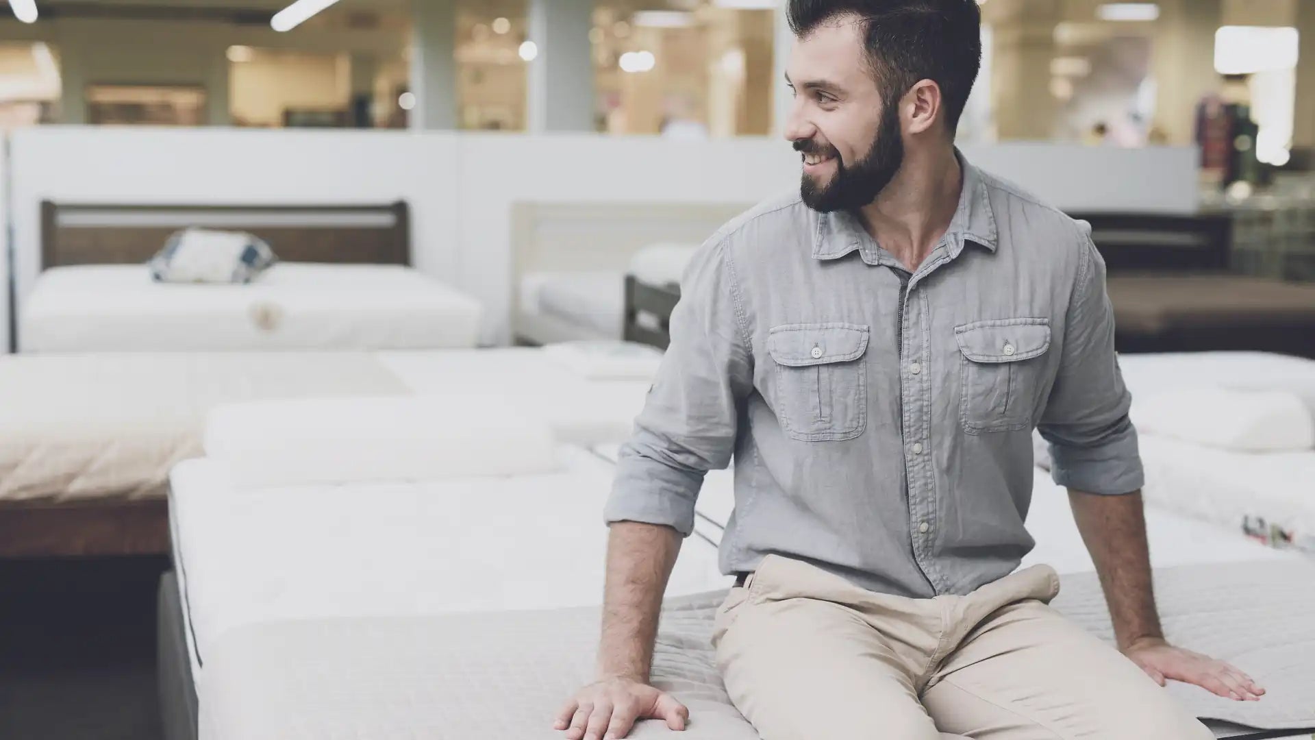 The customer trying to get a feel of the mattress by sitting down following the bed shopping guide